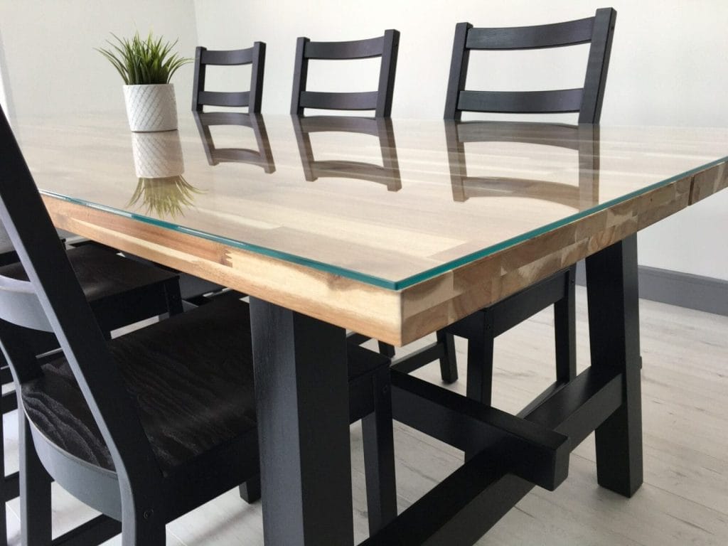 A clear glass tabletop highlighting the natural wood base beneath, creating a sophisticated dining experience