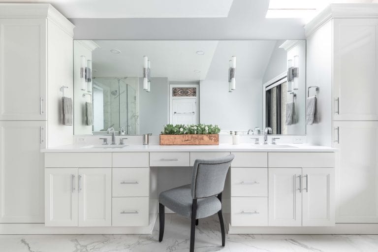 Bright bathroom with a custom mirror and modern white cabinetry.