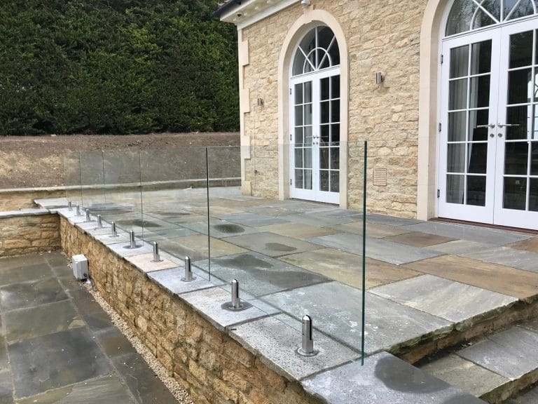 Modern patio featuring a sleek custom glass railing for safety and unobstructed views.
