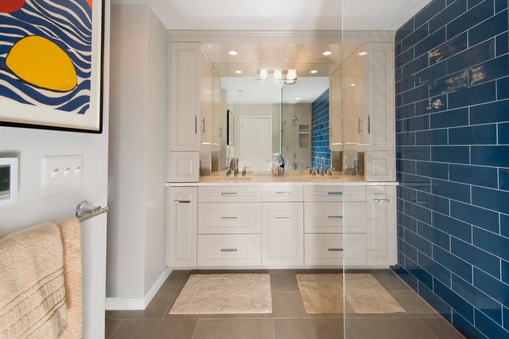 Contemporary bathroom with beige cabinetry, large custom mirror, and bold blue subway tile accent wall.