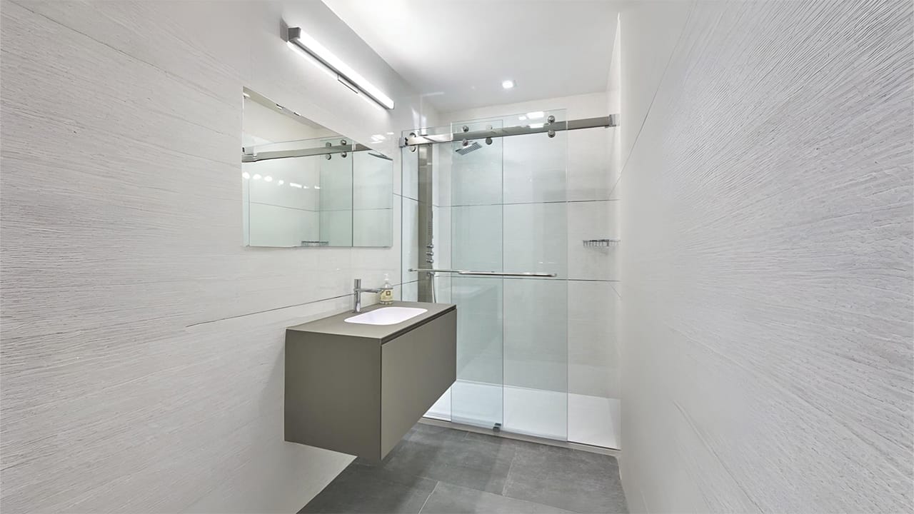 A modern bathroom showcasing custom glass solutions with a sleek sliding enclosure and stainless steel hardware.
